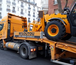 Camion Kiloutou livrant une pelleteuse sur un chantier à Paris.