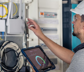 Electricien intervenant sur un tableau électrique dans un logement collectif.