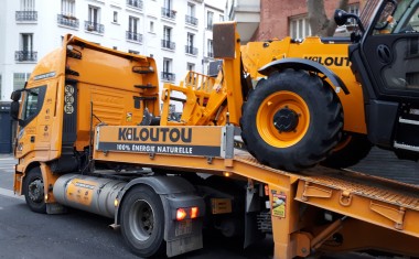 Camion Kiloutou livrant une pelleteuse sur un chantier à Paris.