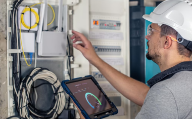 Electricien intervenant sur un tableau électrique dans un logement collectif.