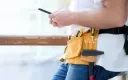 Artisan utilisant son smartphone pour un suivi de chantier.