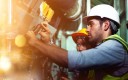 Technicien de maintenance intervenant sur des conduites industrielles dans une usine.